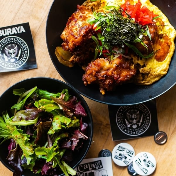 Aburaya Japanese fried chicken with omelet, pickled ginger, seaweed, and a side salad on a wooden table.