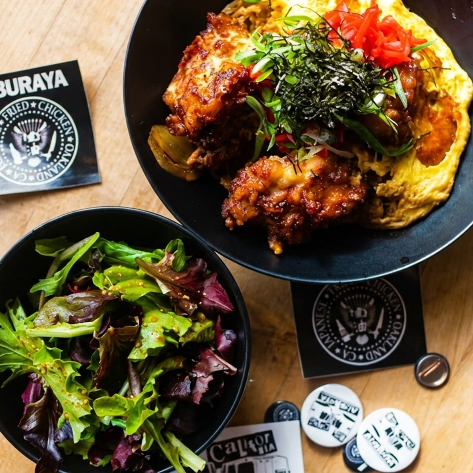 Aburaya Japanese fried chicken with omelet, pickled ginger, seaweed, and a side salad on a wooden table.
